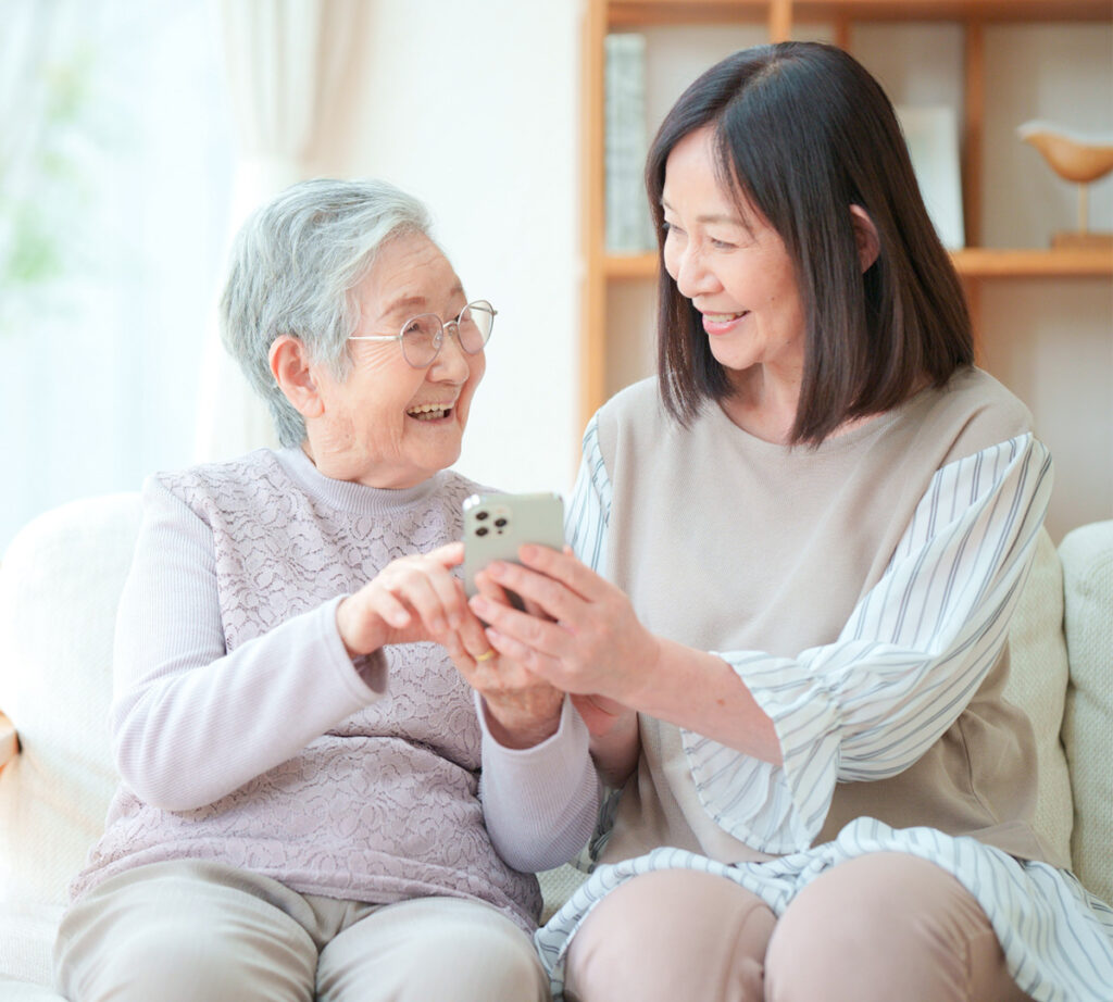 笑顔でスマートフォンを眺める高齢者女性