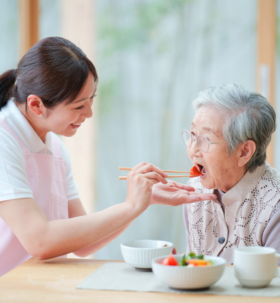 高齢者の食事介護するスタッフ